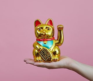 写真：手の上に金色の招き猫が乗っています。