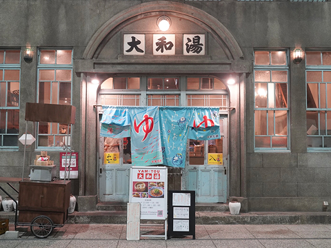 写真：大和湯ゆーゆーの入口。青い暖簾に「ゆ」と書いています